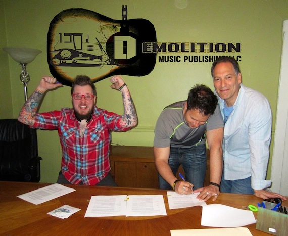 Pictured, (L-R): Adam Searan and Jason Eustice sign contracts on the first official day of business for Demolition Music Publishing, Nashville, during a meeting with songwriter Jon DAgostino, the firms president and CEO.