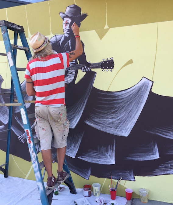 Mike Shine paints a mural on the side of Carnival Music.